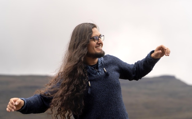 happy latin male traveler with long hair beard and glasses traveling in the wilderness