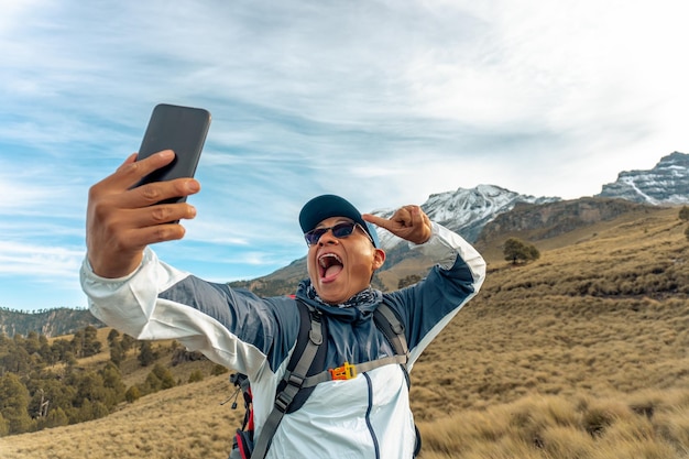 Happy latin man hiker taking a selfie on mountain edge