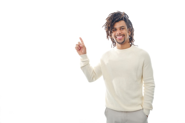 Happy latin man pointing with his finger to an empty space to show something while standing on an isolated background. Advertisement concept.