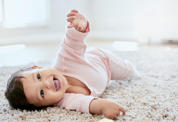 Photo happy laughing and baby on floor in home for child development wellness and growth family childhood and fun of young infant in living room for learning to crawl playing and relax in house