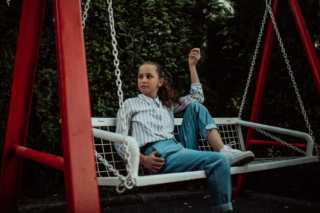 Happy laughing girl posing on swing in sunset summer