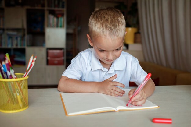 Happy lefthanded boy writing in the paper book with his left hand international lefthander day