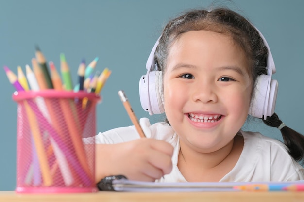 A Happy little asian girl studying online learning class with online video call zoom teacher at home