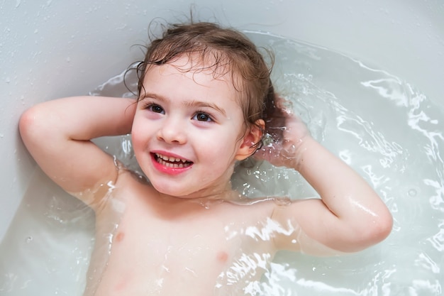 Happy little baby girl face swimming in the bathroom.