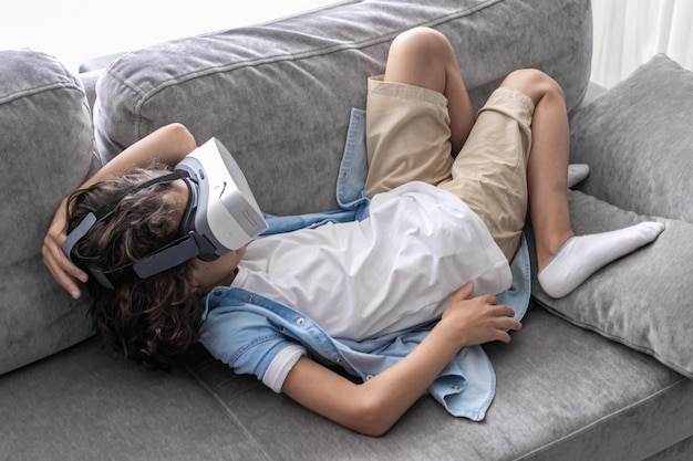 Happy little boy child using virtual reality headset vr glasses gesturing at home having fun