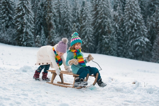 Happy little boy and girl sledding in winter kids sibling riding on snow slides in winter son and da