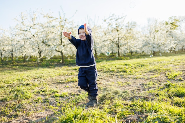 A happy little boy is running in a blooming garden Happy childhood