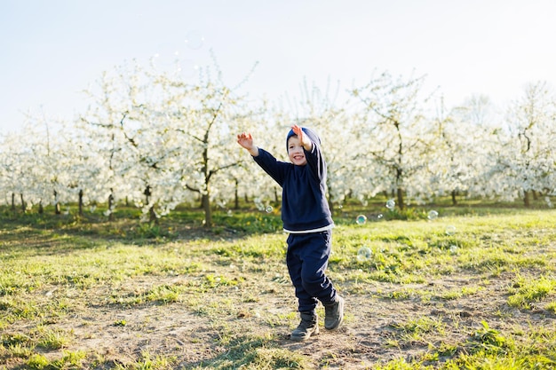 A happy little boy is running in a blooming garden Happy childhood