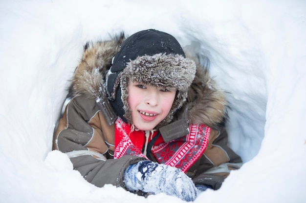 Happy little boy lies in a snowdrift Child in winter