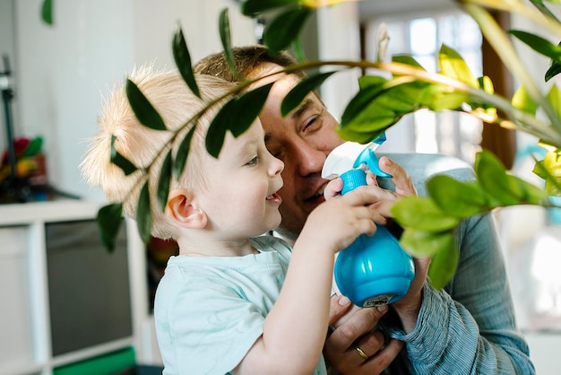 Happy little boy and man plash water on a home flower Father dad and toddler son having fun