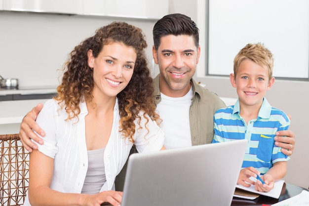 Happy little boy using laptop with parents at table