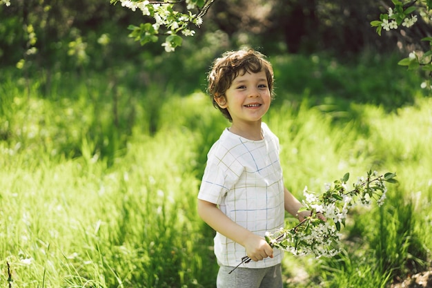 Happy little boy walking in spring garden Child playing with branch of an cherry tree and having fun Kid exploring nature Baby having fun Spring activity for inquisitive children