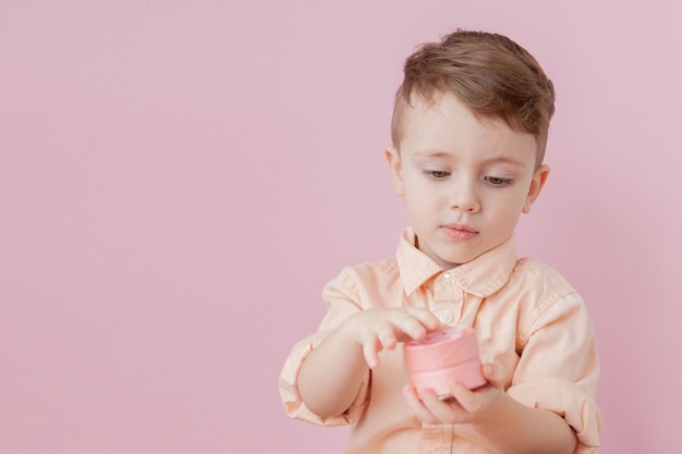 Happy little boy with a gift . Photo isolated on pink . Smiling boy holds present box.  of holidays and birthday