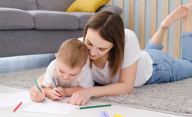 Happy little child boy hand drawing pictures with mom