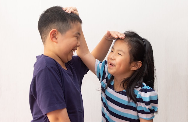 Happy little girl and boy measuring their height