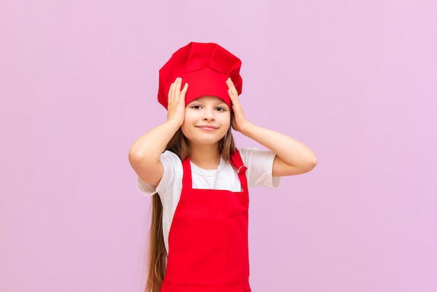 A happy little girl in a chef's costume is very happy and smiling the girl loves very much to help the teachers in the kitchen