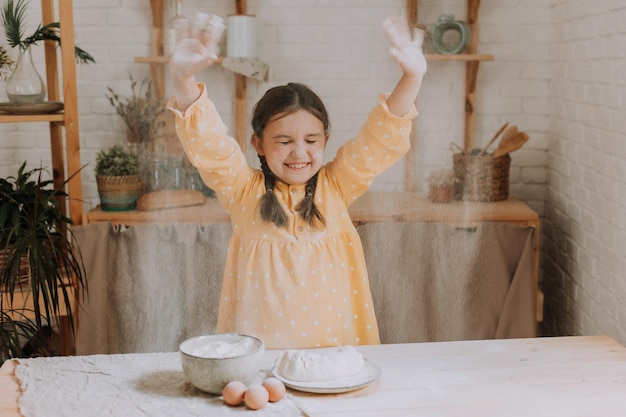 happy little girl cooks a pie in the kitchen in a cotton dress. High quality photo