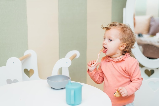 Happy little girl eating applesauce at home