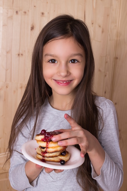 Happy little girl eating traditional Russian pancakes with berry jam. Maslenitsa concept