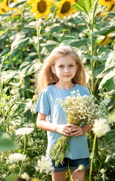 Happy little girl on the field of sunflowers in summer.