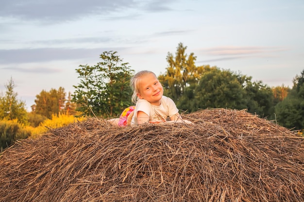 Happy little girl on a haystack in the countryside