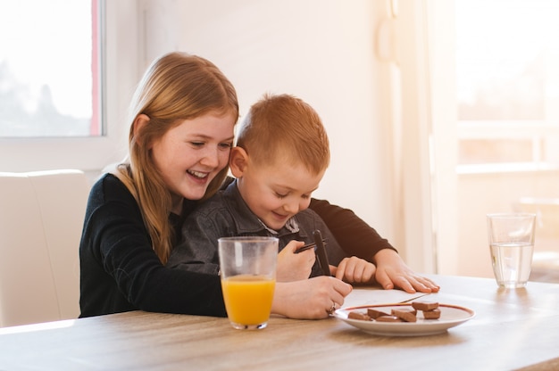 Happy little girl and her brother writting on paper