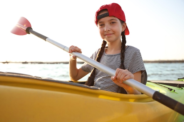 Happy little girl kayaking on river Summer camp activity