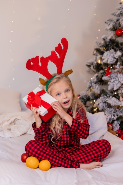 happy little girl in pajamas at home rejoices and unpacks presents for Christmas. High quality photo