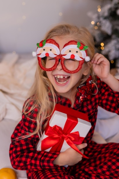 happy little girl in pajamas at home rejoices and unpacks presents for Christmas. High quality photo