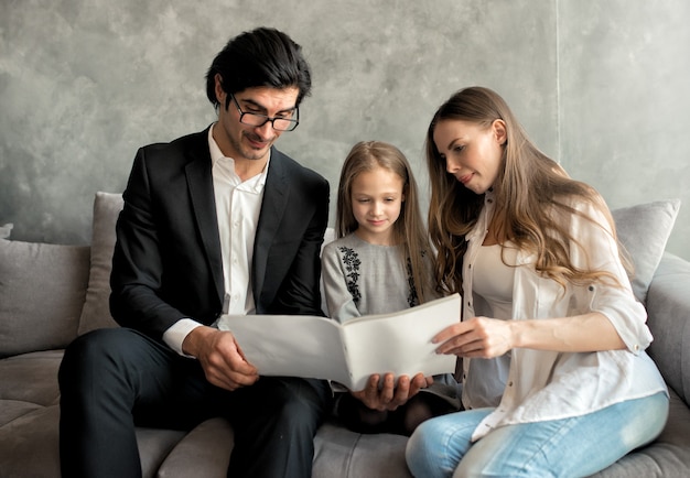 Happy little girl reads a book with her parents at home