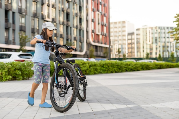 Happy little girl riding a bike in the city