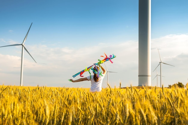 Happy Little girl running in a wheat field with a kite in the summer