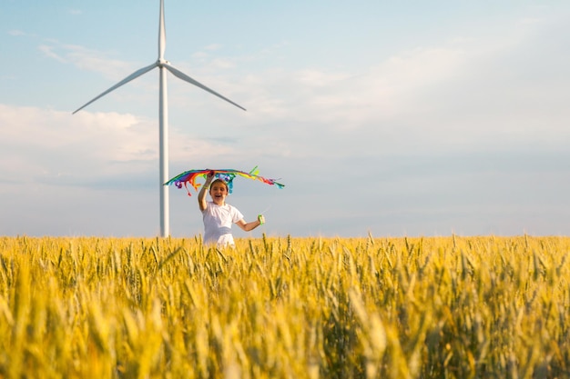 Happy Little girl running in a wheat field with a kite in the summer