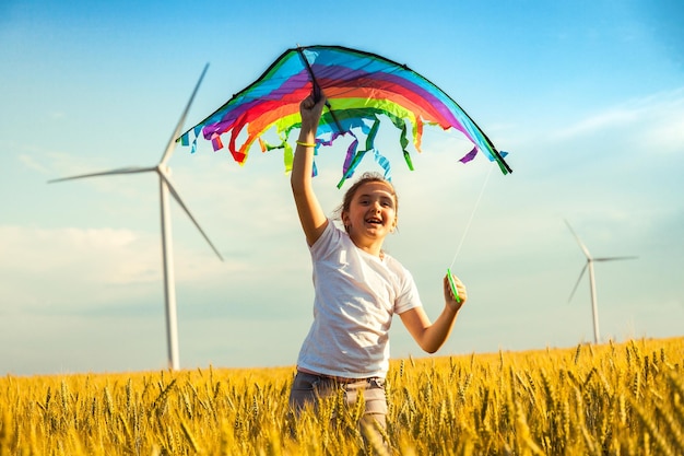 Happy Little girl running in a wheat field with a kite in the summer