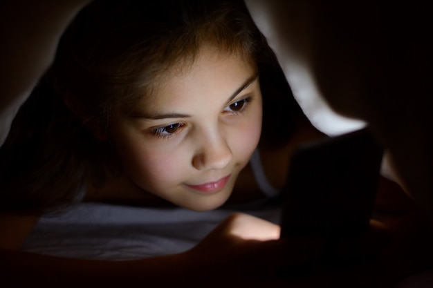 Happy little girl sending messages to her friends using mobile phone