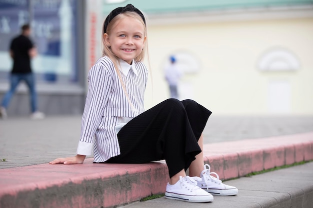 A happy little girl sits on the steps of the store