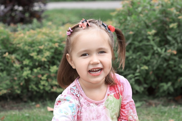 Happy little girl sitting on the lawn on a summer day