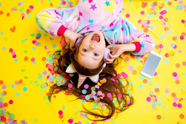 Happy little girl in a unicorn Kigurumi on a yellow background