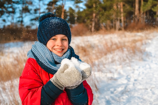 Happy little girl walking in winter forest in sunny day