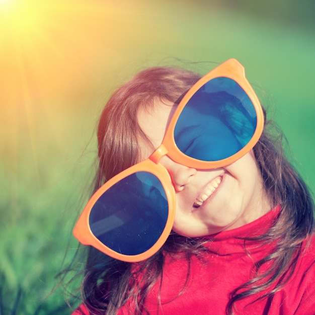 Happy little girl with big sunglasses looking at the sun