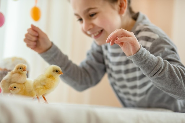 Happy little girl with little chickens on easter decor background