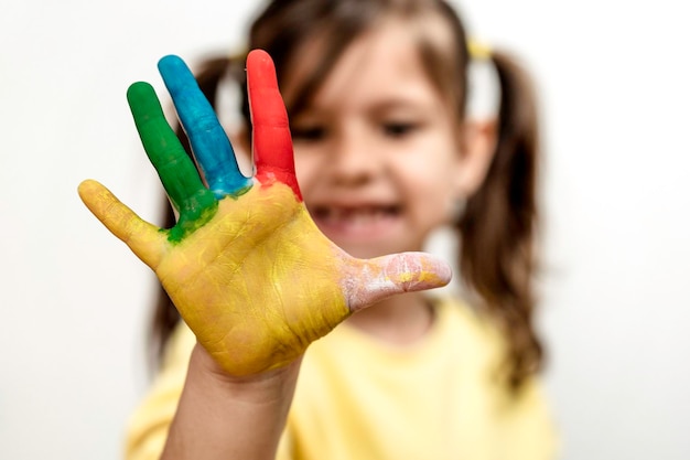 Happy little girl with the painted hand laughing and having fun Little girl who is painting her hands Leisure activity and childhood concept