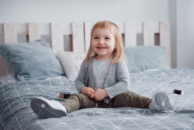 Happy little girl with a pillow in bed at home