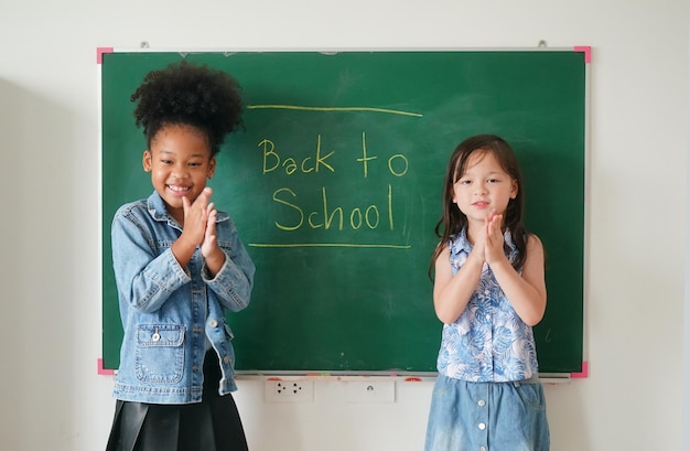 Happy little Girls against Chalkboard With Back To School