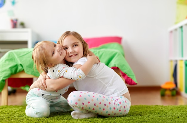 Photo happy little girls or sisters hugging at home