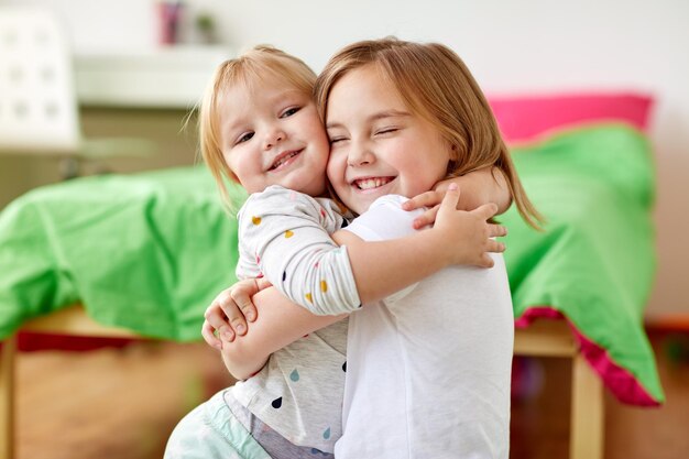 Photo happy little girls or sisters hugging at home