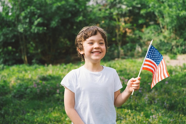 Happy little patriotic boy holding American flag USA celebrate 4th of July Happy independence day