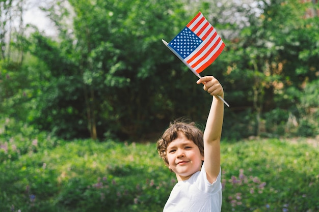 Happy little patriotic boy holding American flag USA celebrate 4th of July Happy independence day