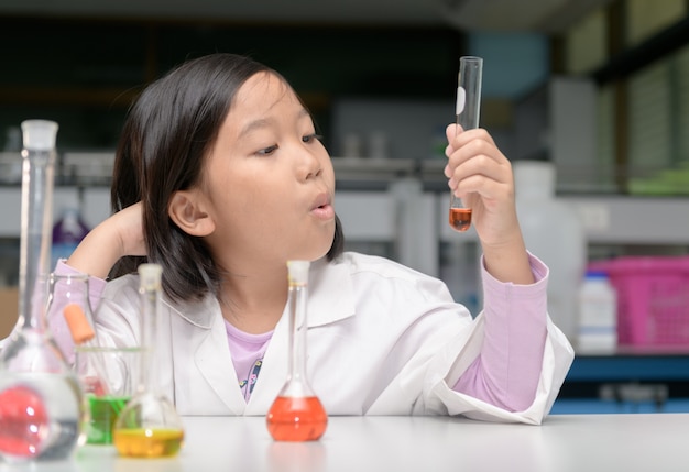 Happy little scientist in lab coat making experiment 