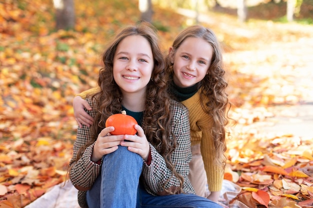 Happy little sisters hugging on an autumn background for halloween